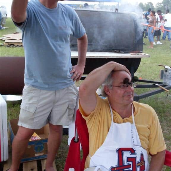 Two men taking a break with the barrel grill in the background