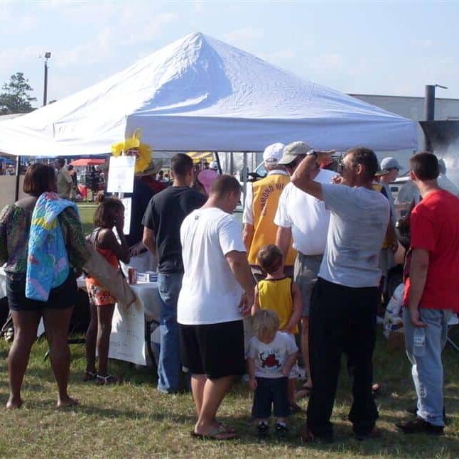 People standing in line waiting to be served from a barbecue barrel cooker