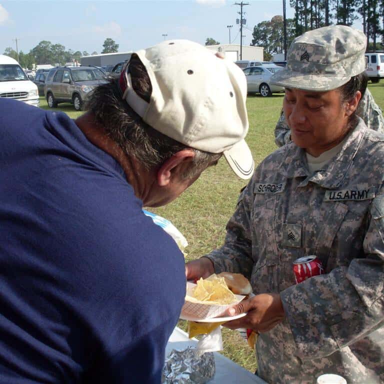 Man wearing a patriotic T-shirt serving a female service member nachos