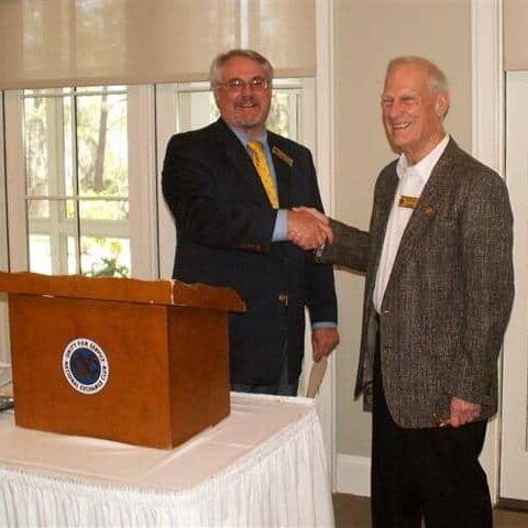 Two men shaking hands at a podium