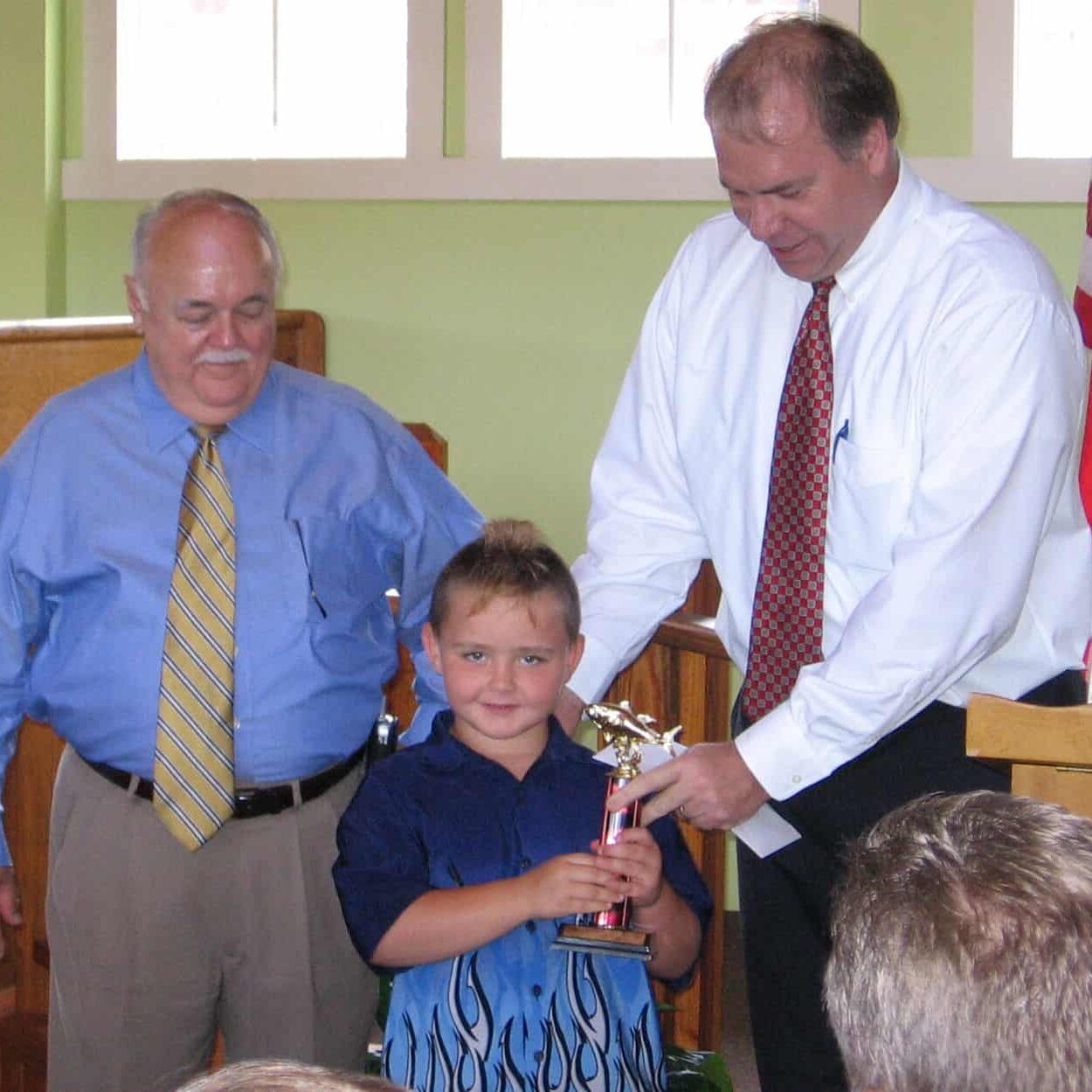 Child being presented with a gold colored fishing trophy