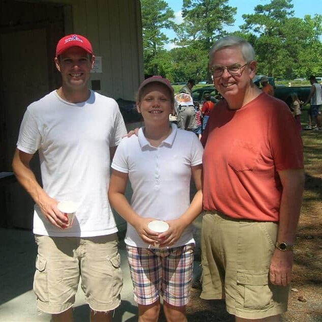 Two men and child enjoying refreshments at a golf event