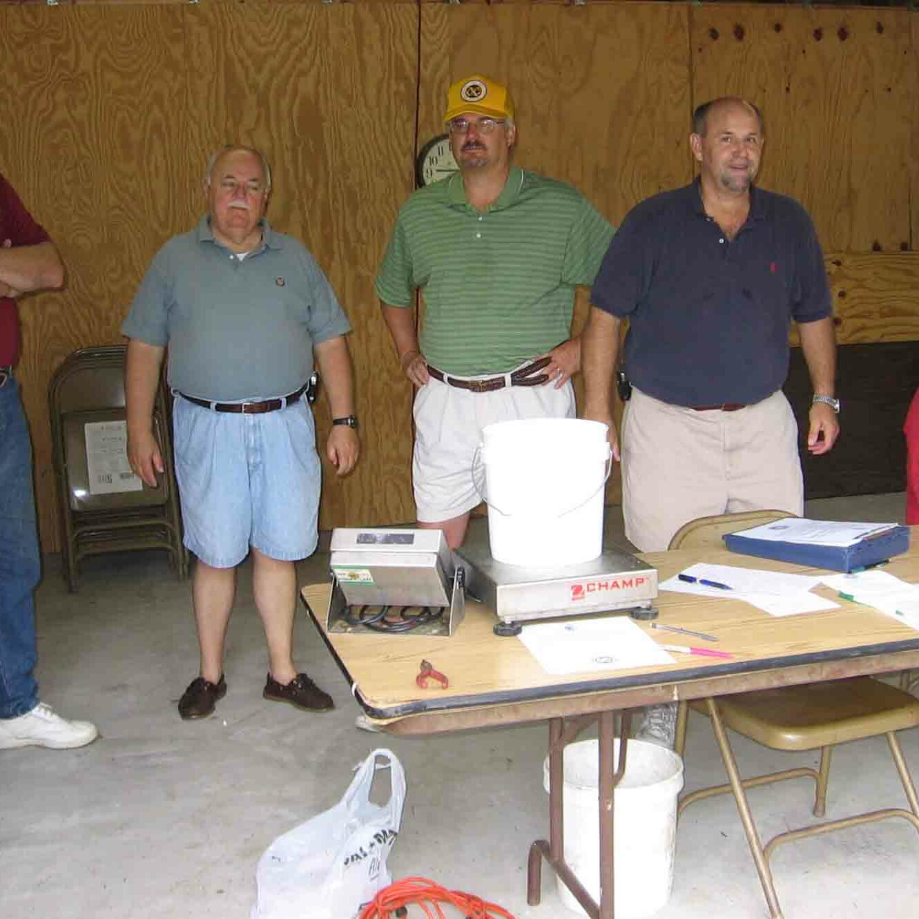 Six men behind a table with a digital scale