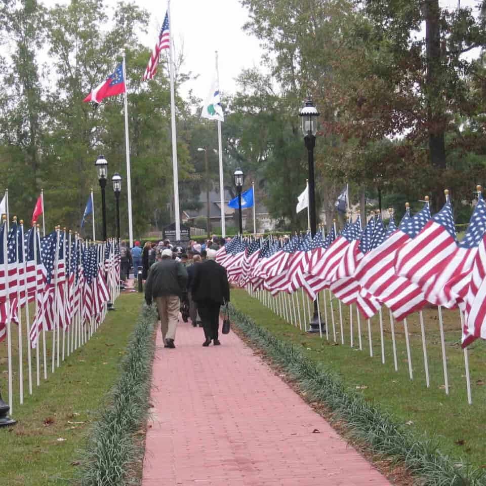 Two vets walk a path lined with American flags