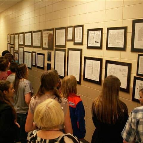 Students looking at a wall of framed documents