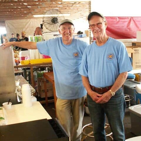 Two men in Exchange Club T-shirts taking a break from serving diners