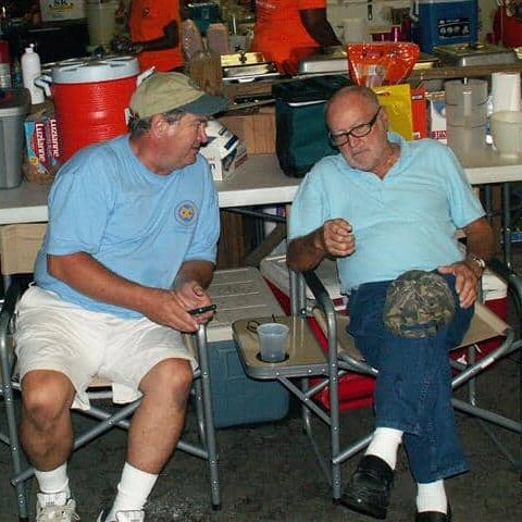 Two men in folding camping chairs conversing