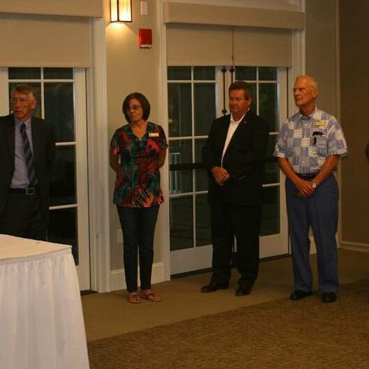 A woman at the Exchange Club podium with one woman and five men standing beside her