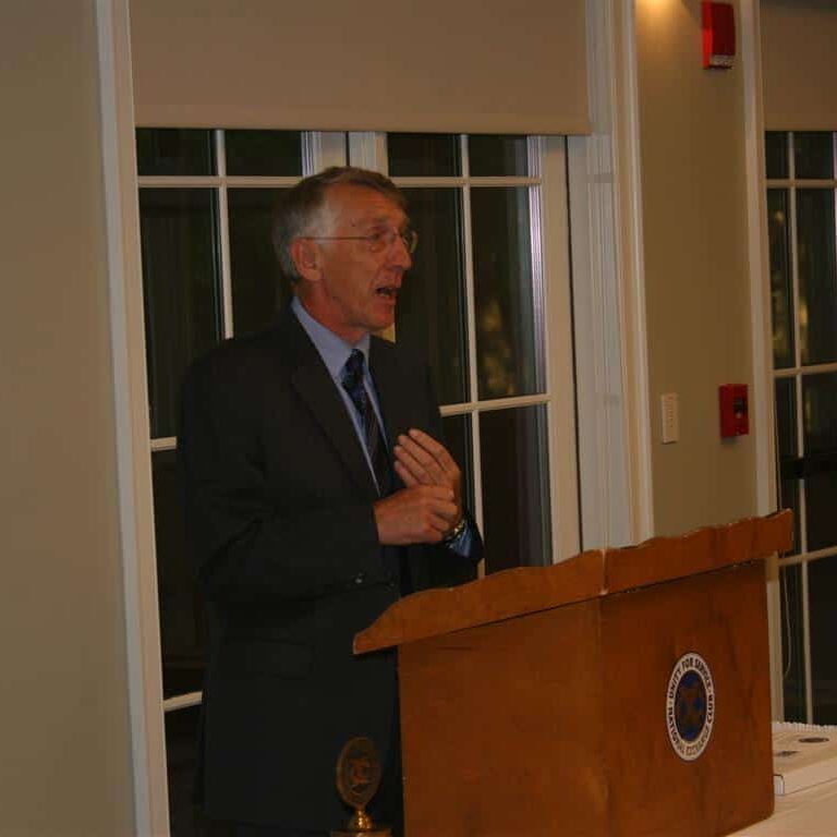 A man in a suit and tie speaking the the Exchange Club podium