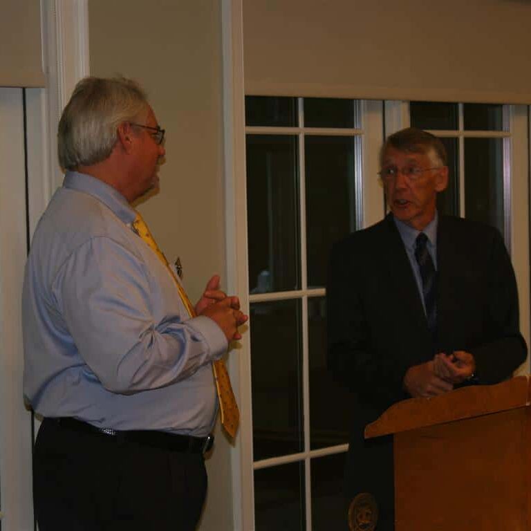 Two men conversing at the Exchange Club podium