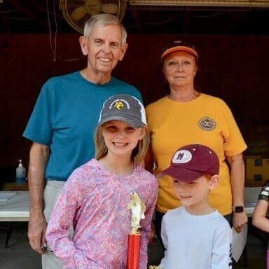 A girl and boy holding a fishing tournament trophy with two Exchange Club members standing behind them