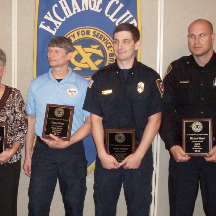 A woman and three men holding Exchange Club plaques in recognition of their safety efforts