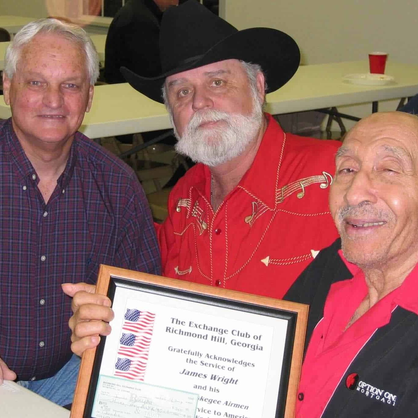 Two men with Mr. James Wright holding a framed Exchange Club certificate and bank check acknowledging his service as a Tuskegee Airman.