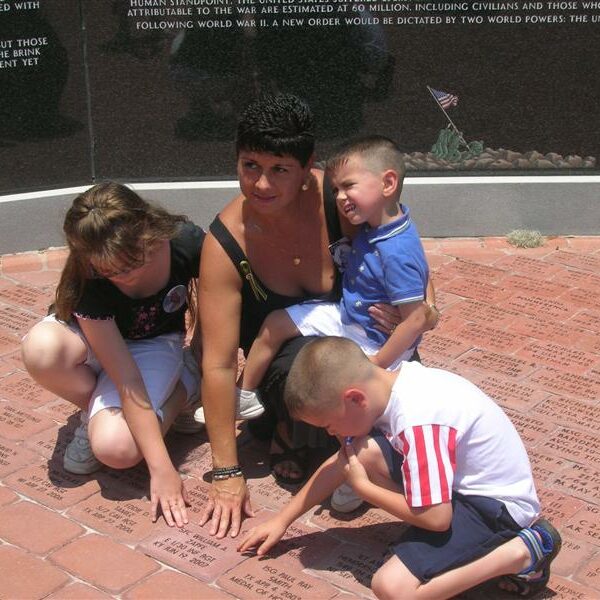 A mother and three children looking at memorial military bricks honoring individual veterans