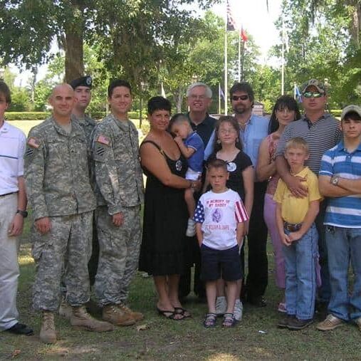 Military families posing at an outdoor veterans ceremony