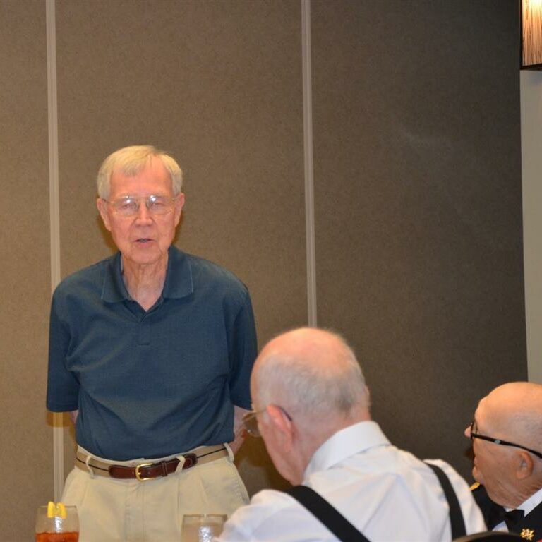 Three elderly veteran gentlemen conversing at a banquet table